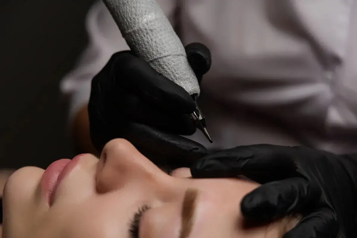 Main de Karine s'apprêtant à pigmenter le sourcil en technique microshading avec dermographe au studio Kanea Tattoo & Beauty Toulon