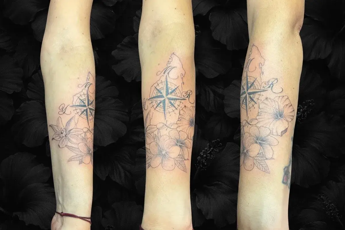 Tatouage floral femme avant-bras avec fleur exotique, boussole et initiale, salon Kanea Toulon
