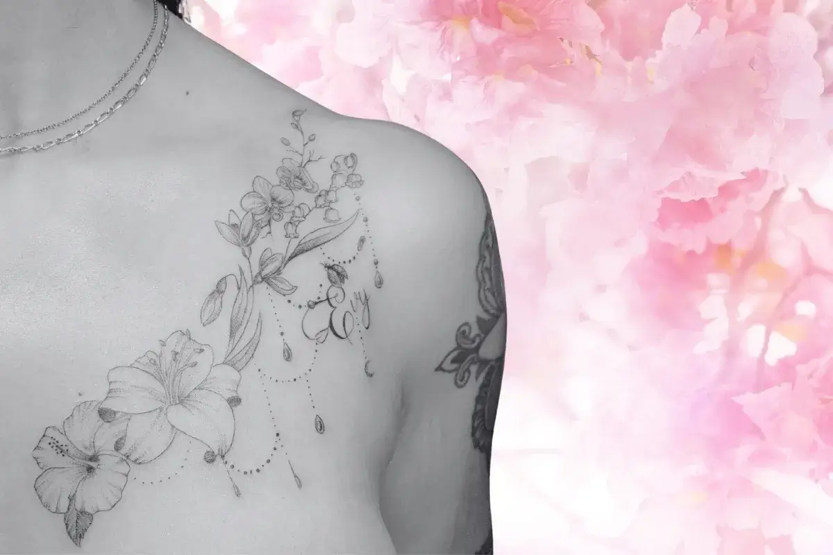Tatouage floral haut du buste avec fleurs, bijoux et prenom au salon Kanea Toulon