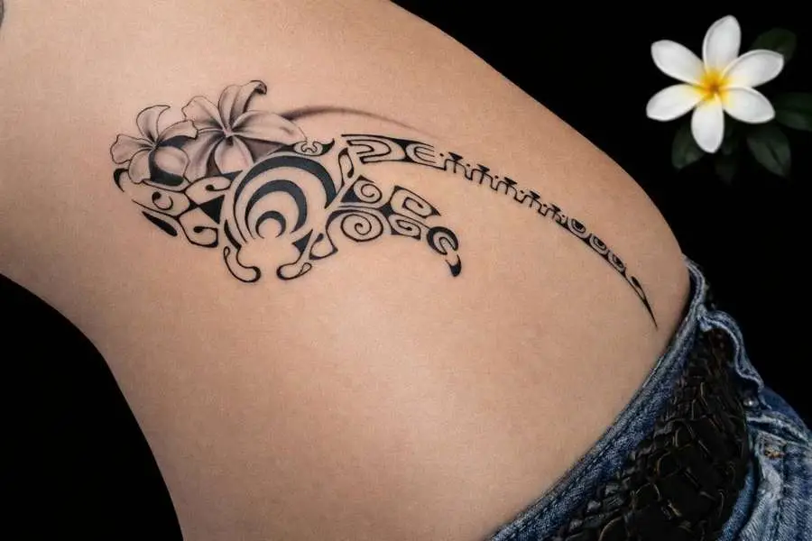 Tatouage polynésien féminin sur hanche avec raie stylisée et fleurs de tiaré réalisé à Toulon par Kanea