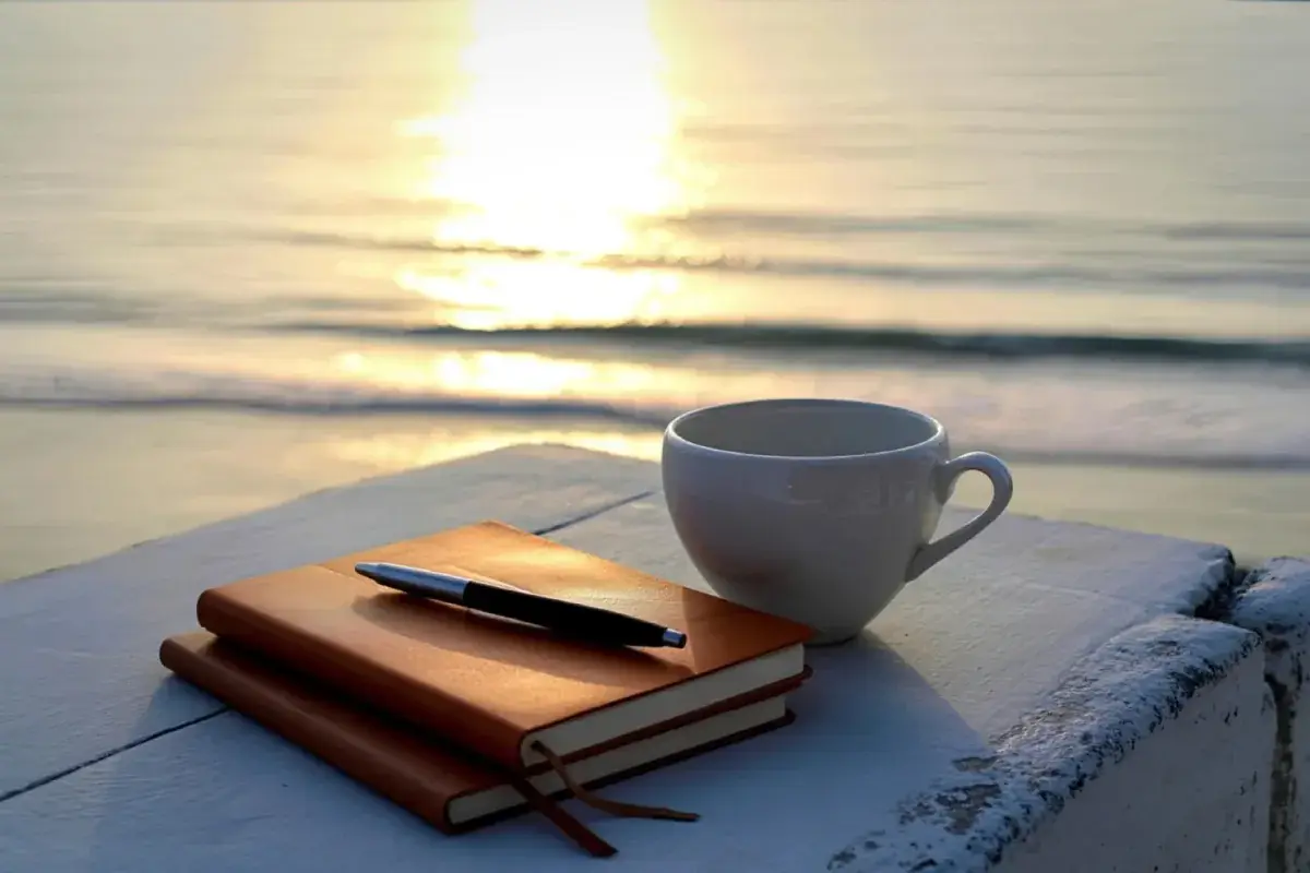Carnet stylo tasse de café face à la mer pour préparer tranquillement son projet de tatouage à Toulon Kanea