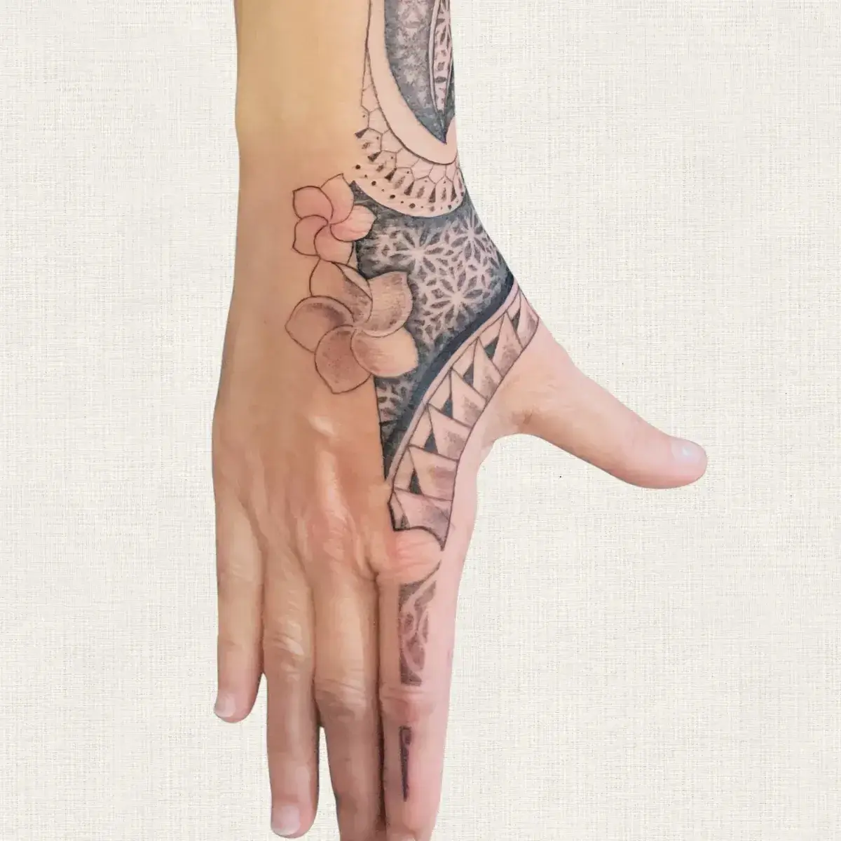 Tatouage polynésien dotwork et frangipanier sur la main, pièce sur-mesure Kanea Toulon