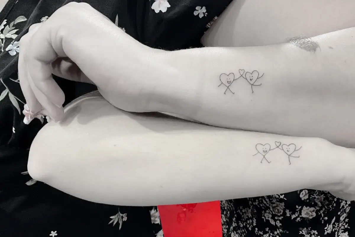 Tatouage minimaliste cœur avec petites jambes pour deux amies sur le bras à Toulon Kanea
