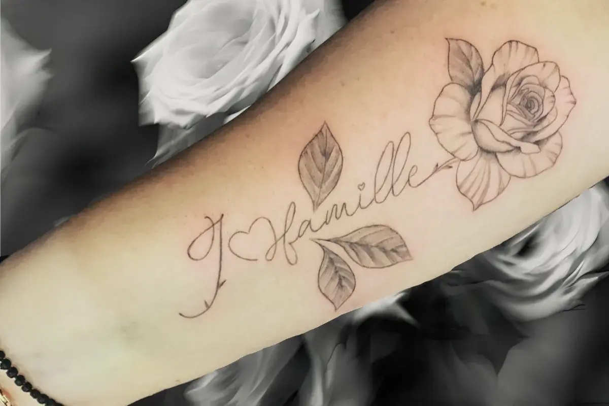 Tatouage minimaliste J'aime ma famille en lettrage fin avec rose sur l'avant-bras à Toulon Kanea
