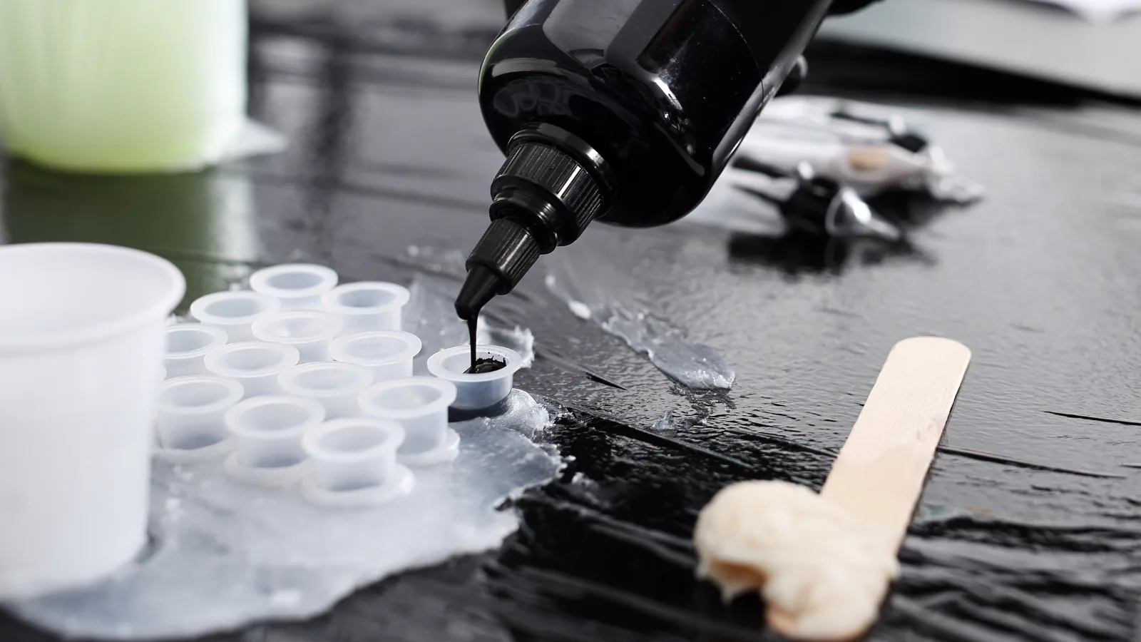 Encre versée dans des godets à usage unique sur un plan de travail protégé, hygiène tatouage Toulon